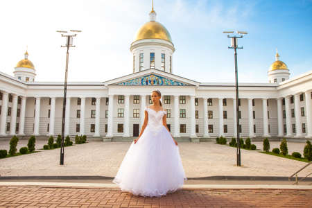 Portrait of a young girl in a white ball gown posing against the background of the Orthodox Cathedralの写真素材