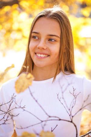Â Full body portrait of a young beautiful blonde girl in white sweater and blue jeans, autumn park outdoorの写真素材