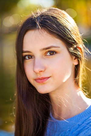 Young beautiful girl in a purple sweater lies on fallen autumn leavesの写真素材