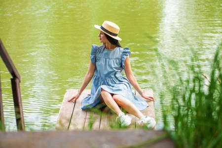 Young beautiful brunette woman in a turquoise summer dress, summer park outdoorsの写真素材