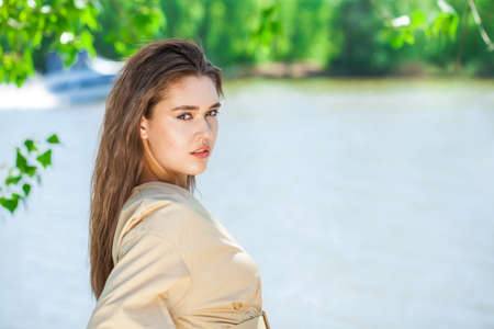 Portrait of a young beautiful brunette woman in beige dress