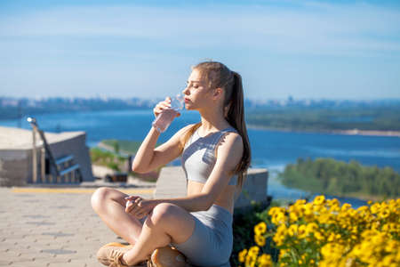 Young beautiful girl in sports uniform is engaged in fitness outdoors