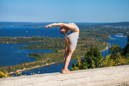 Young beautiful girl in sports uniform is engaged in fitness outdoorsの写真素材