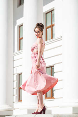 Full length portrait of young beautiful brunette woman in pink dressの写真素材