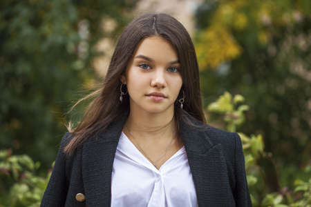 Portrait of a young beautiful brunette girl posing in summer parkの写真素材