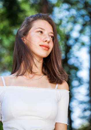 Portrait of a young beautiful brown-haired girl with freckles on her faceの写真素材