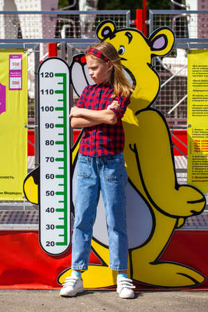 Portrait of a red-haired little girl in a black hat walks in the autumn parkの写真素材