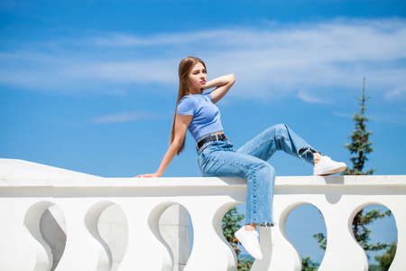 Back rear view blonde hair model in blue jeans, summer park outdoor