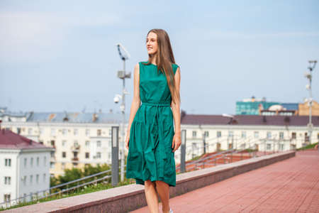 Full body portrait of a young beautiful brunette woman in green dressの写真素材