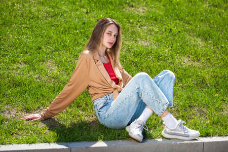 Full body portrait of a young beautiful blonde girl in blue jeans, summer park outdoors