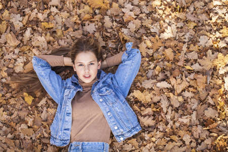 Young beautiful blonde girl lies on the lawn, summer park outdoors