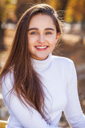Close up portrait of young brunette girl posing in autumn parkの写真素材