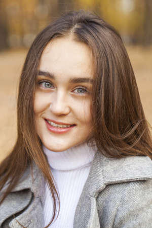 Close up portrait of young brunette girl posing in autumn park