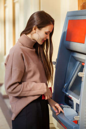 Young beautiful brunette woman in red coat posing on winter park. Model wearing stylish warm clothes.の写真素材