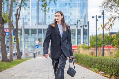 Young beautiful woman in male business suit posing on the streetの写真素材