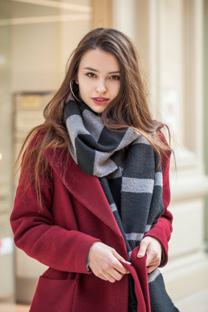 Portrait of a young beautiful girl in a red coatの写真素材