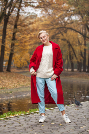 Happy beautiful middle-aged woman walking in autumn parkの写真素材