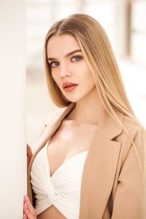 Portrait of a young beautiful blonde woman in a beige jacketの写真素材