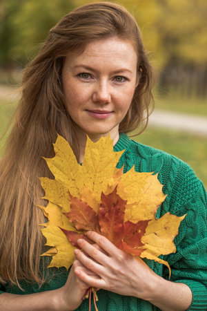 Young beautiful red-haired woman walking in autumn parkの写真素材