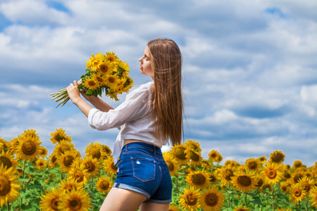 Portrait of a young beautiful girl with a bouquet of sunflowersの写真素材