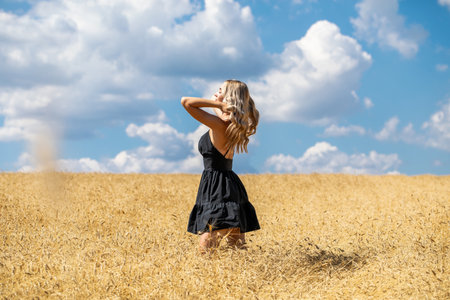 Portrait of a young beautiful blonde girl in black summer dressの写真素材