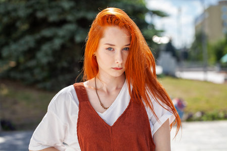 Close up portrait of a young beautiful red hair girl in a summer park