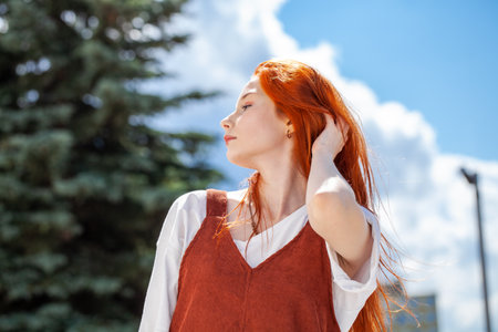 Close up portrait of a young beautiful red hair girl in a summer parkの写真素材