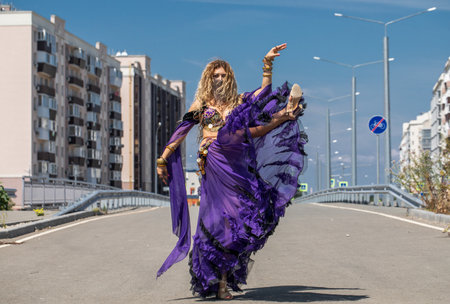 Eastern dance. Young beautiful woman in a purple costume dances on the streetの写真素材