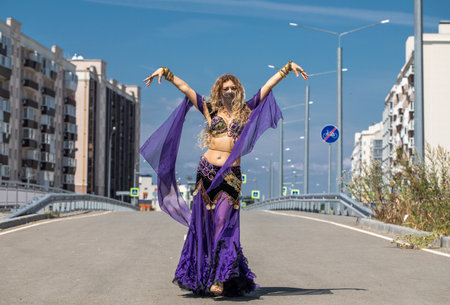 Eastern dance. Young beautiful woman in a purple costume dances on the streetの写真素材