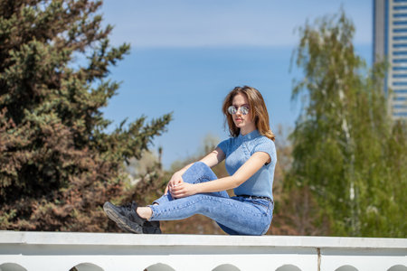 Young girl in blue jeans posing on the embankmentの写真素材