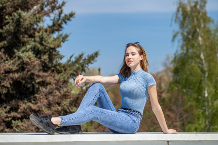 Young beautiful girl in blue jeans posing on the embankmentの写真素材