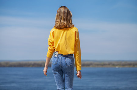 Young girl in blue jeans posing on the embankmentの写真素材