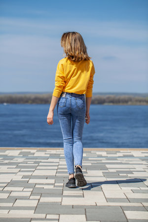Young girl in blue jeans posing on the embankmentの写真素材