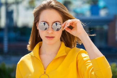 Close up portrait of a young beautiful blonde girl in summer streetの写真素材