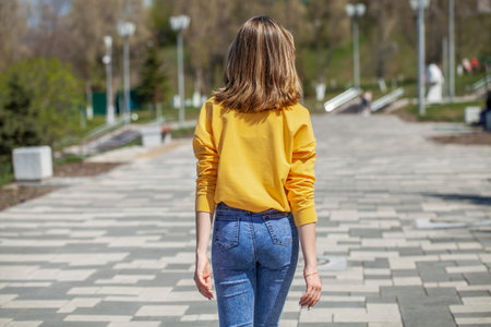 Back view, portrait of a young woman in blue jeansの写真素材