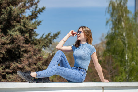 Young girl in blue jeans posing on the embankmentの写真素材