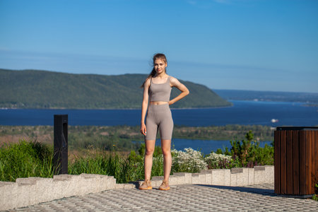 A young girl in a tracksuit performs physical exercises in a summer parkの写真素材