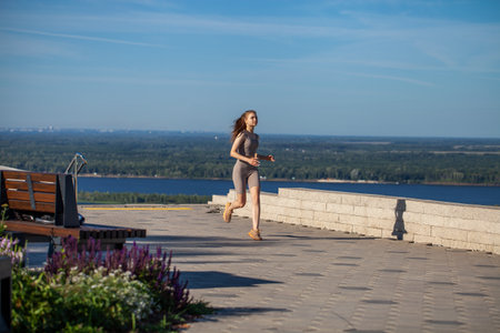A young girl in a tracksuit performs physical exercises in a summer parkの写真素材