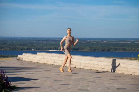 A young girl in a tracksuit performs physical exercises in a summer parkの写真素材