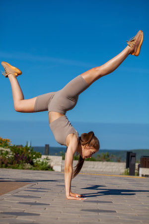 Fitness portrait young athletic woman doing gymnastics on blue sky backgroundの写真素材
