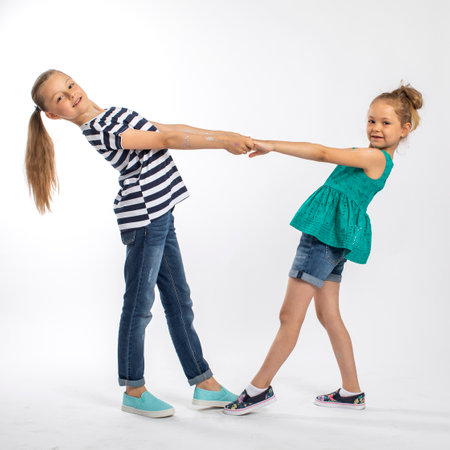Full length portrait of two beautiful girls sisters, isolated on white backgroundの写真素材
