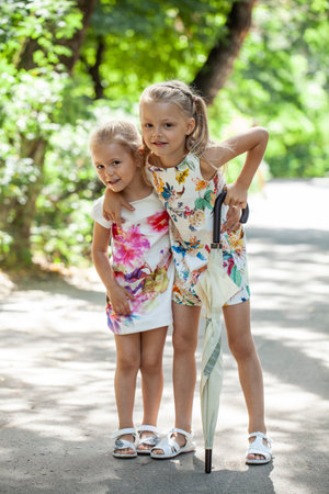 Two little girls in summer dresses and with an umbrellaの写真素材