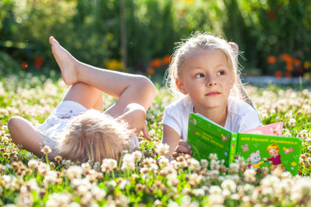 Summer holidays in the village - two girls lying on the lawnの写真素材