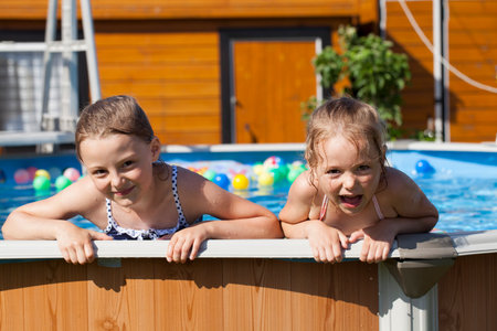 Two Happy sisters in bikini swimming poolの写真素材