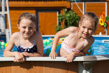 Two sisters in bikini swimming poolの写真素材