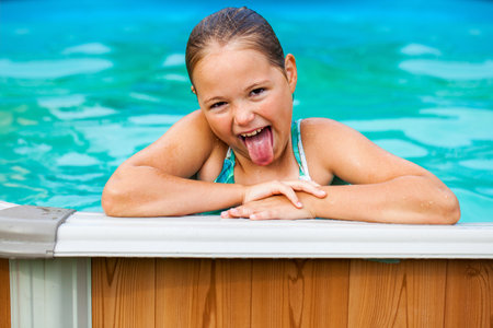 Cheerful teenage girl swimming in the pool in the backyardの写真素材