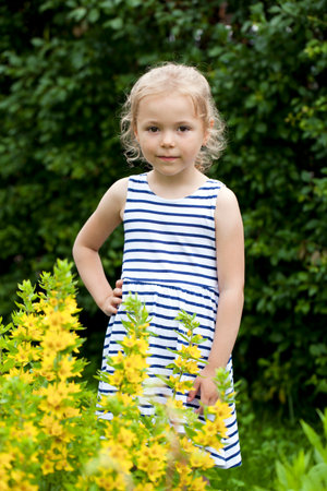 Portrait of beautiful happy little girl, against background of summer parkの写真素材