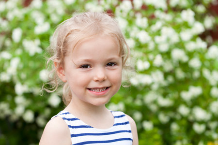 Portrait of beautiful happy little girl, against background of summer parkの写真素材