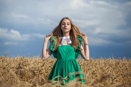 Portrait of a young beautiful blonde woman posing in a wheat fieldの写真素材