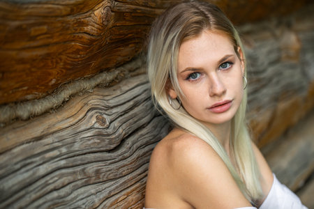 Close up portrait of a young blonde woman against the background of an old wooden wallの写真素材